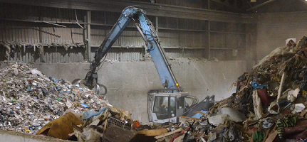 image of municipal waste and a grab machine inside a waste facility